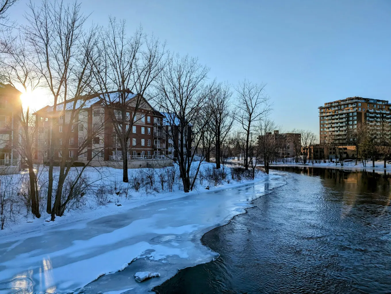 Immeubles résidentiels en bordure d'une rivière à Laval en hiver illustrant les secteurs desservis